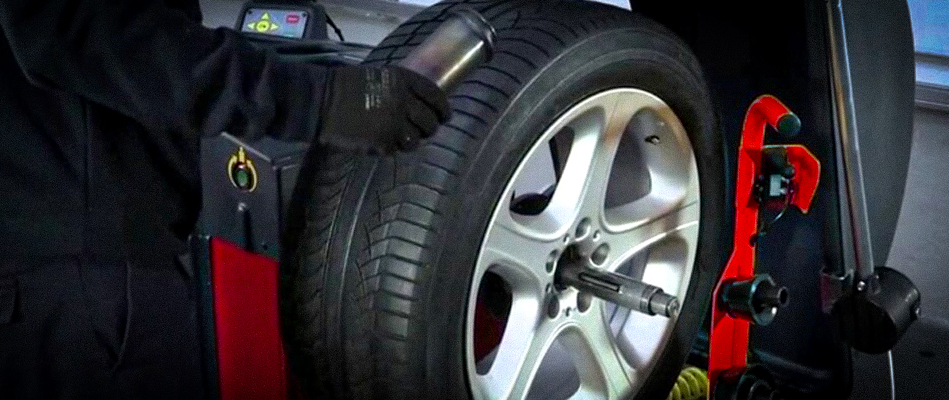 echnician performing wheel balancing on a car tyre